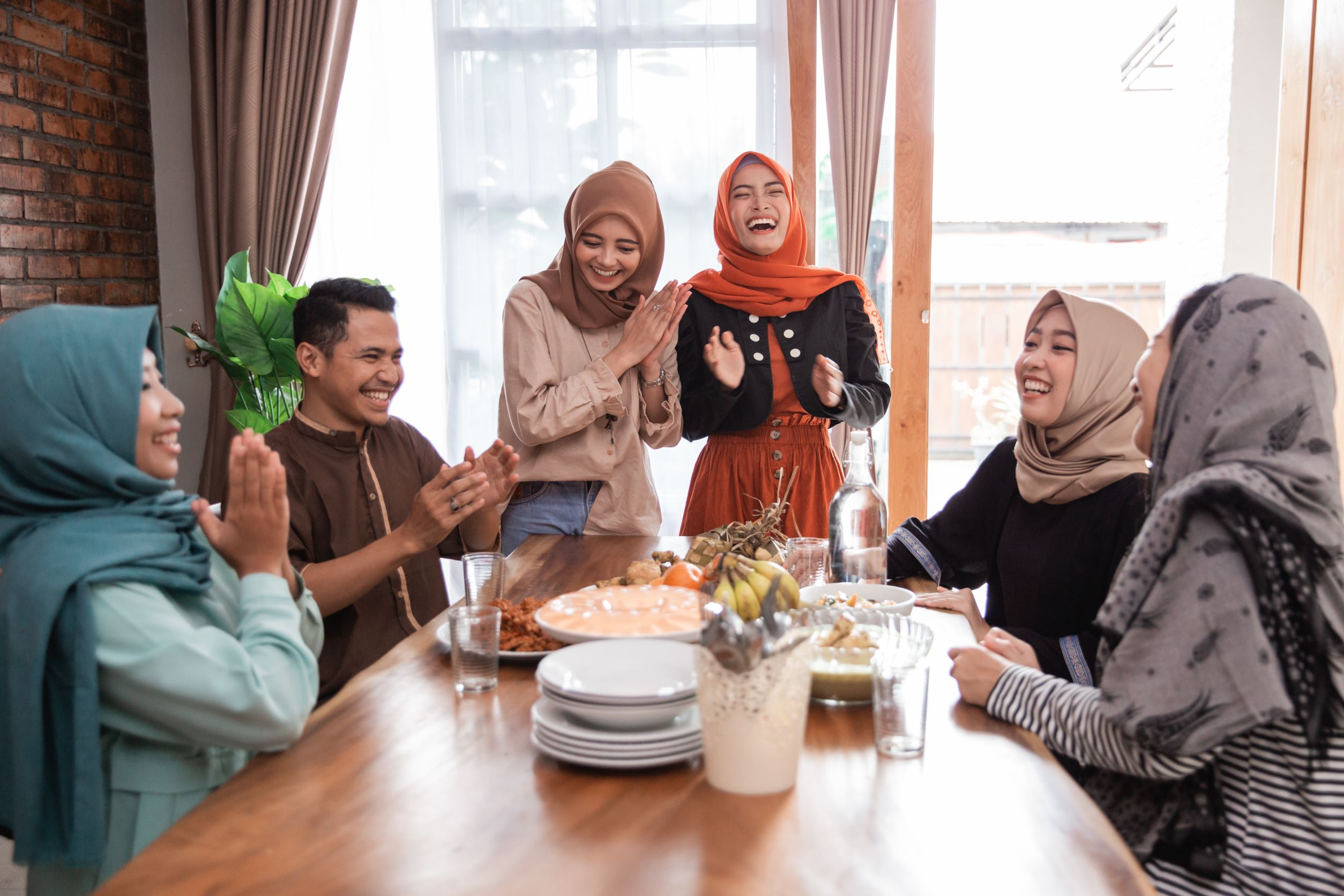 A group of women and one guy seating around the table laughing.