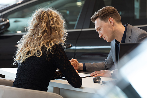 Woman and man seating across from each other at a desk looking at paperwork